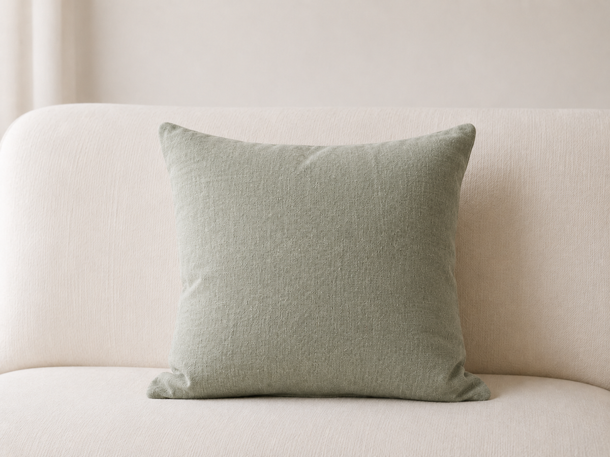 Coussin en lin vert sauge posé sur un canapé blanc